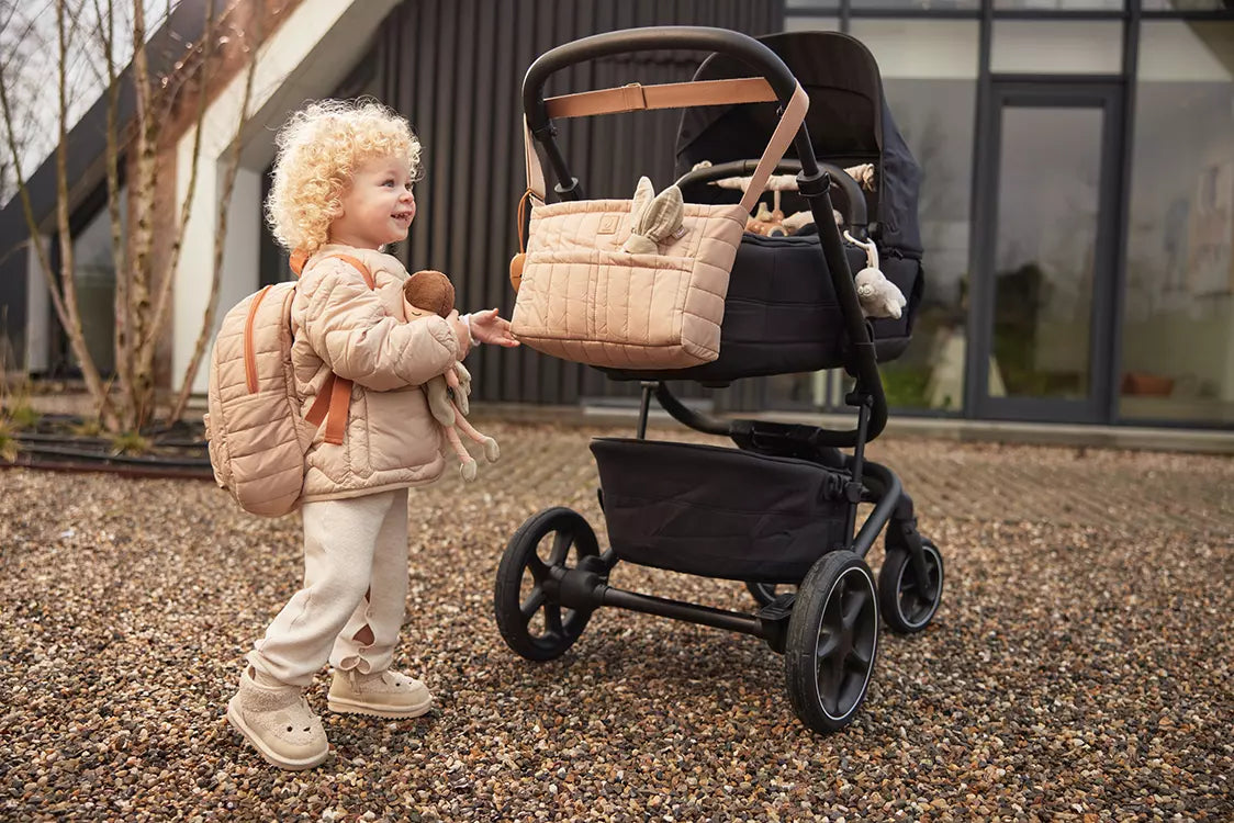 a kid with Jollein Buggy Organizer Puffed Biscuit hanging on a buggy