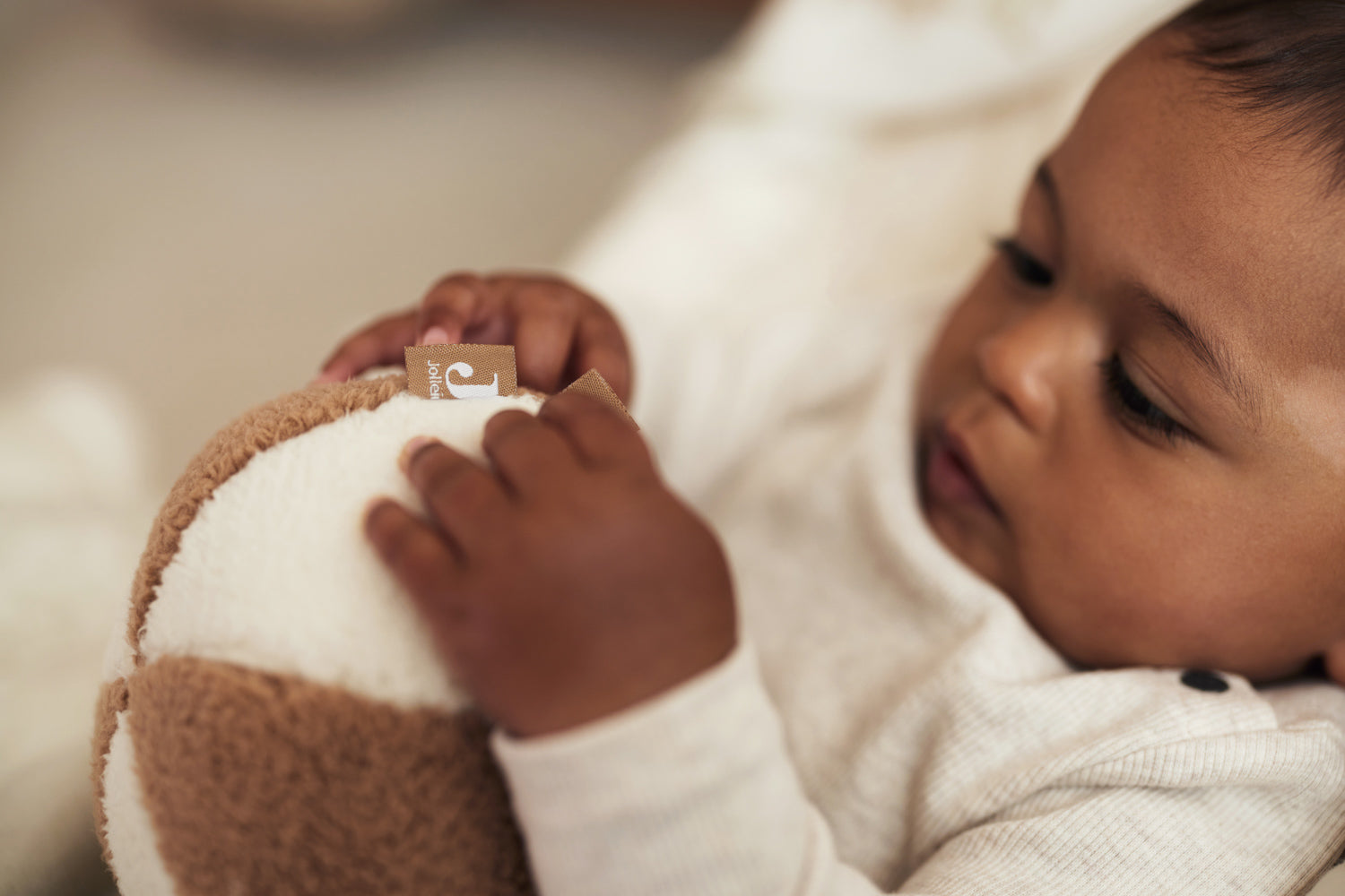 close up of a baby holding the Jollein soft play ball in ivory and biscuit