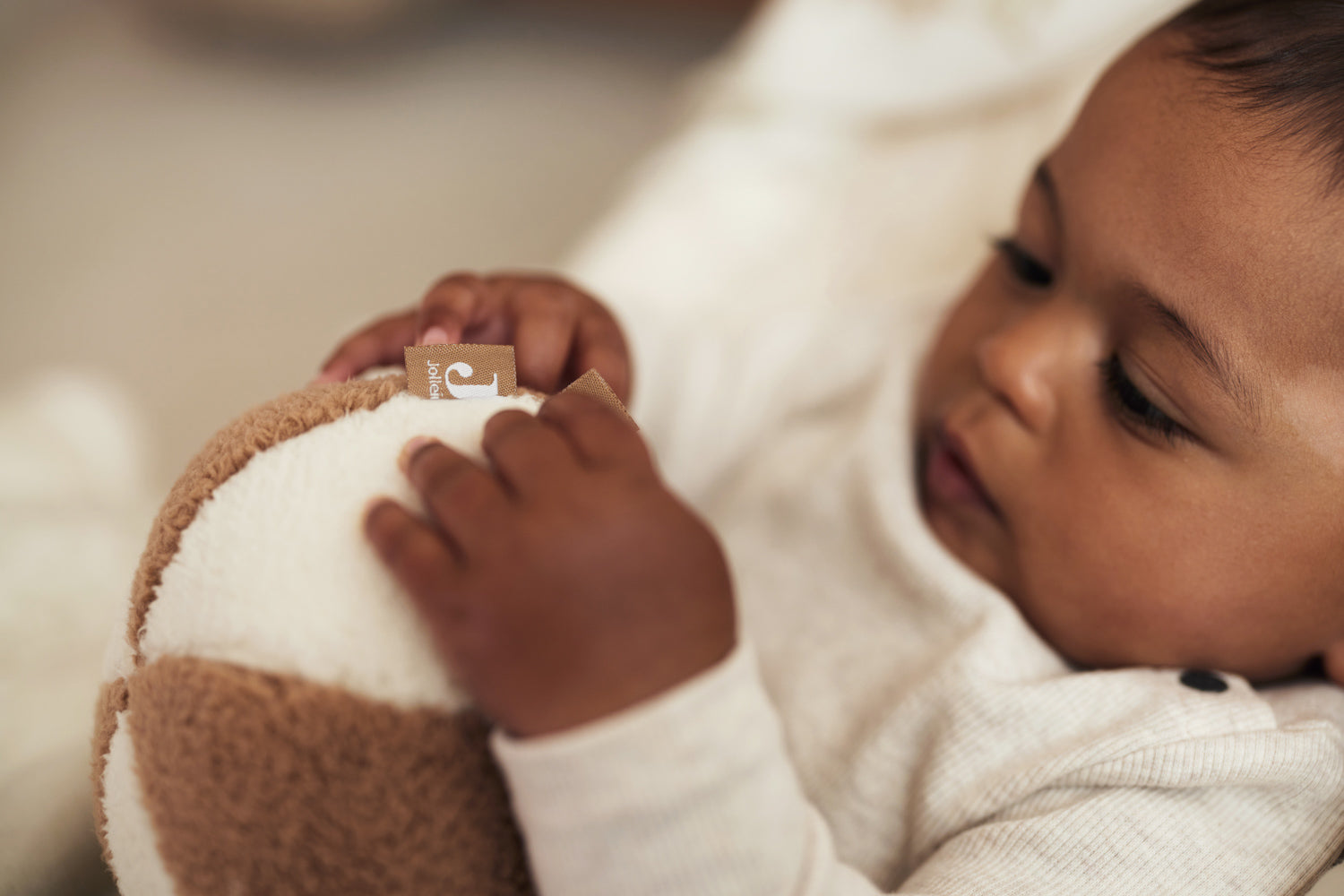 close up of a baby holding the Jollein soft play ball in ivory and biscuit 