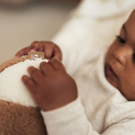 close up of a baby holding the Jollein soft play ball in ivory and biscuit