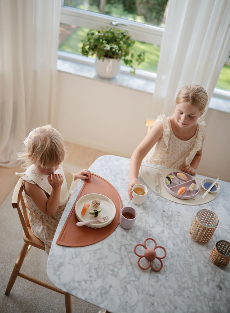 Girls eating with Mushie Rattle Teether Daisy on the table