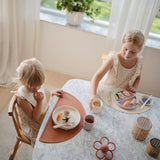 Girls eating with Mushie Rattle Teether Daisy on the table