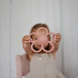 Girl holding the Mushie Rattle Teether Daisy