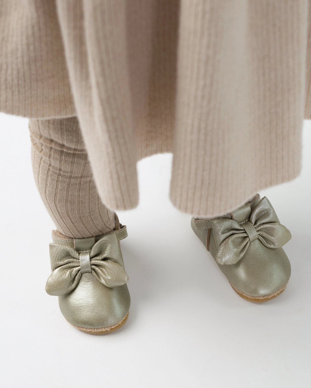 Donsje Celie baby shoes in Champagne Metallic Leather, worn with a beige outfit