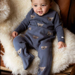 Donsje Phlyn Koalas onesie in Dark Spruce, worn by a baby on a chair