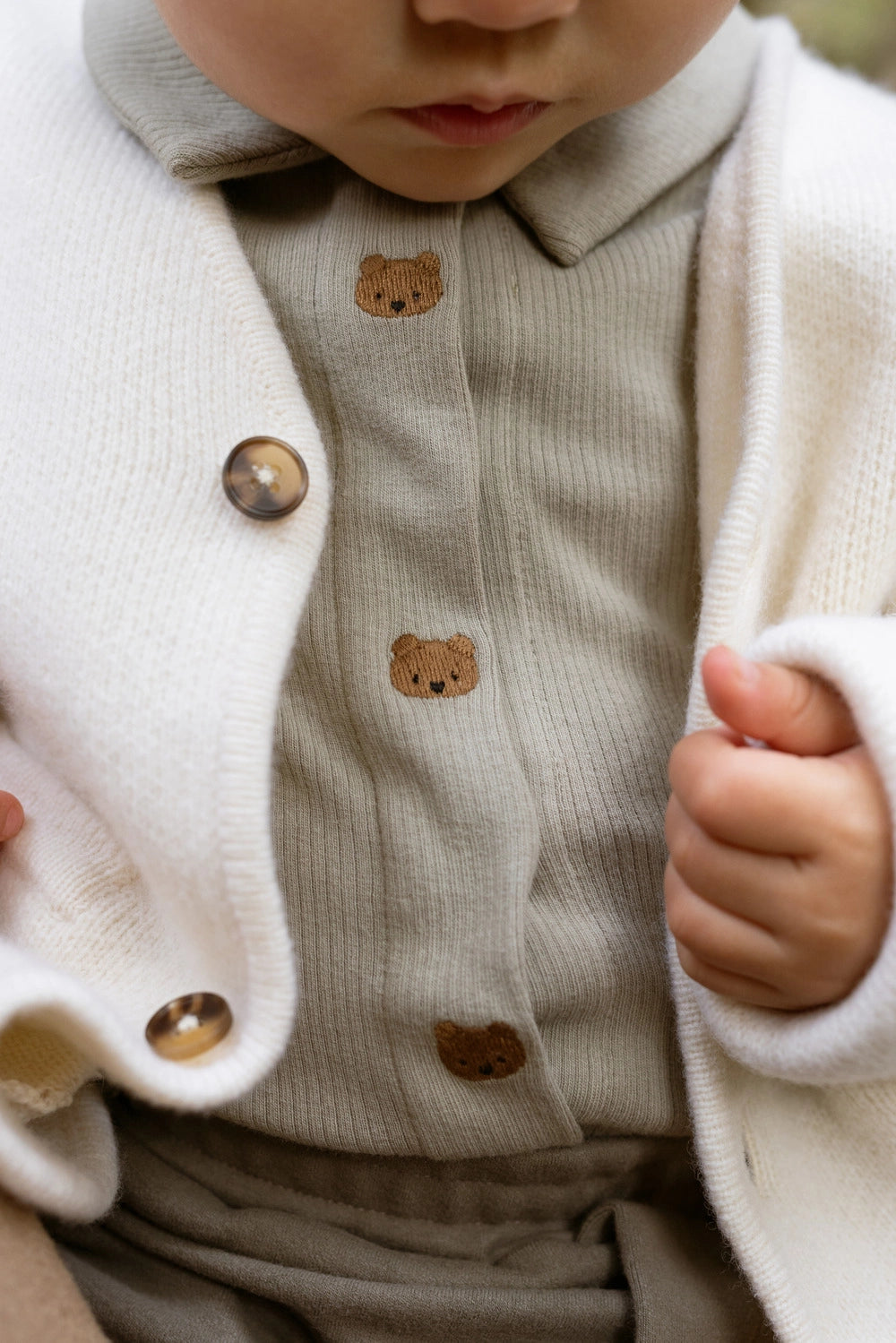 Donsje Finnian Bears bodysuit in Dusty Green, worn by a child, close-up of the collar and buttons