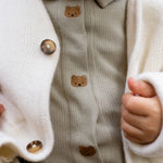 Donsje Finnian Bears bodysuit in Dusty Green, worn by a child, close-up of the collar and buttons