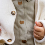 Donsje Finnian Bears bodysuit in Dusty Green, worn by a child, close-up of the collar and buttons