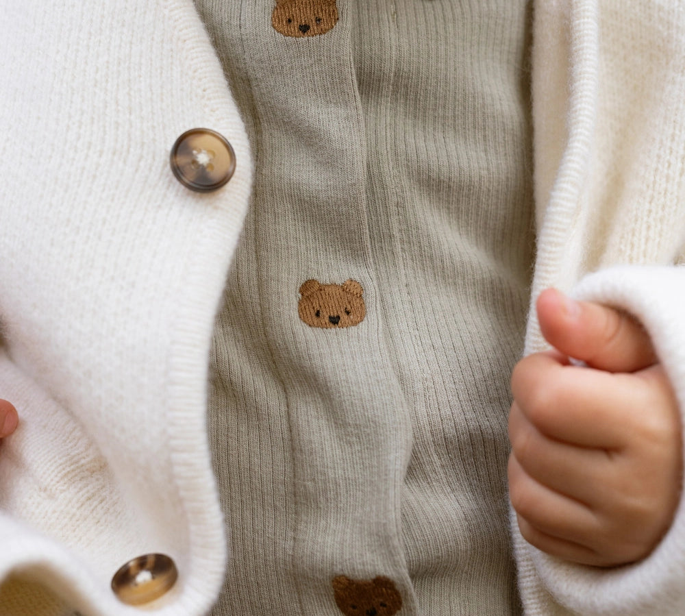 Donsje Finnian Bears bodysuit in Dusty Green, worn by a child, close-up of the collar and buttons
