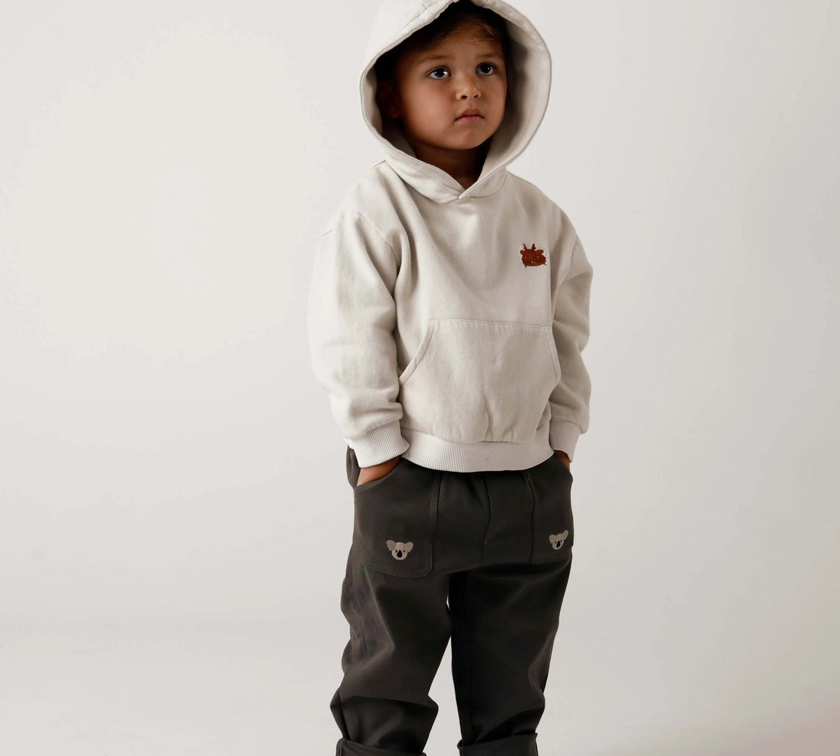 Donsje Kassim Koala trousers in Cloudy Grey, worn by a child with a hooded top