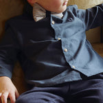 Donsje Chee shirt in Night Blue, worn by a seated child