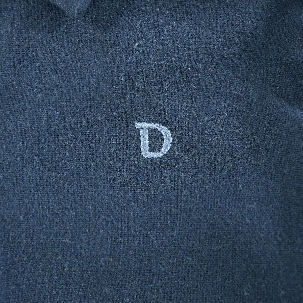 Donsje Chee shirt in Night Blue, close-up of the embroidered D detail