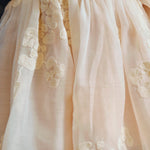 Donsje Kylen dress in Soft Powder with White Blossom, worn by a child, close-up of the skirt and floral details