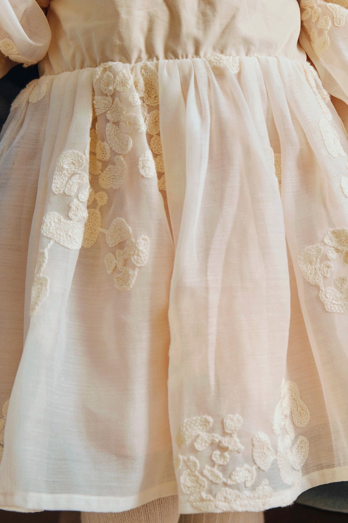 Donsje Kylen dress in Soft Powder with White Blossom, worn by a child, close-up of the skirt and floral details