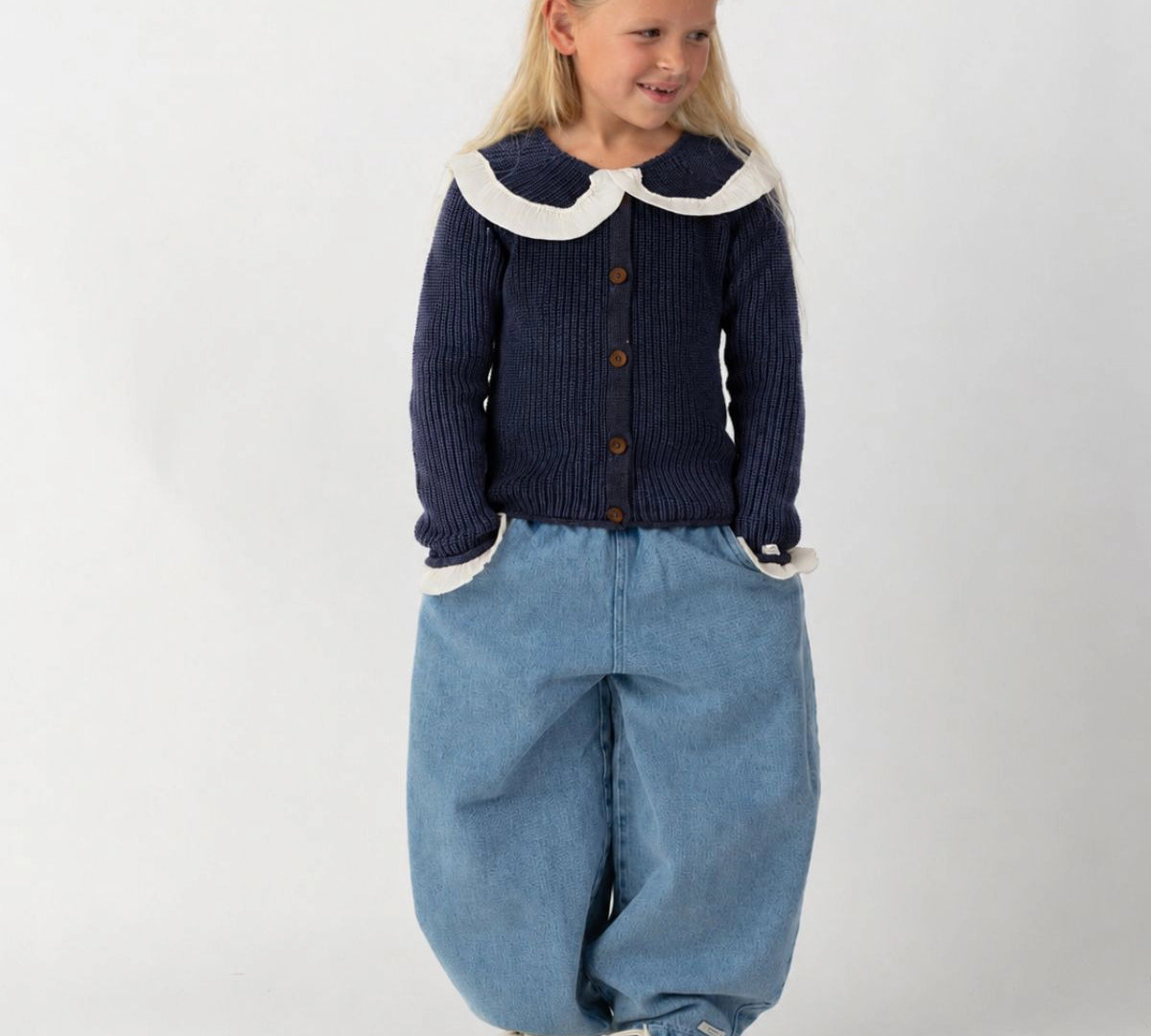 Donsje Dinotje trousers in Sky Blue, worn by a child with a navy cardigan