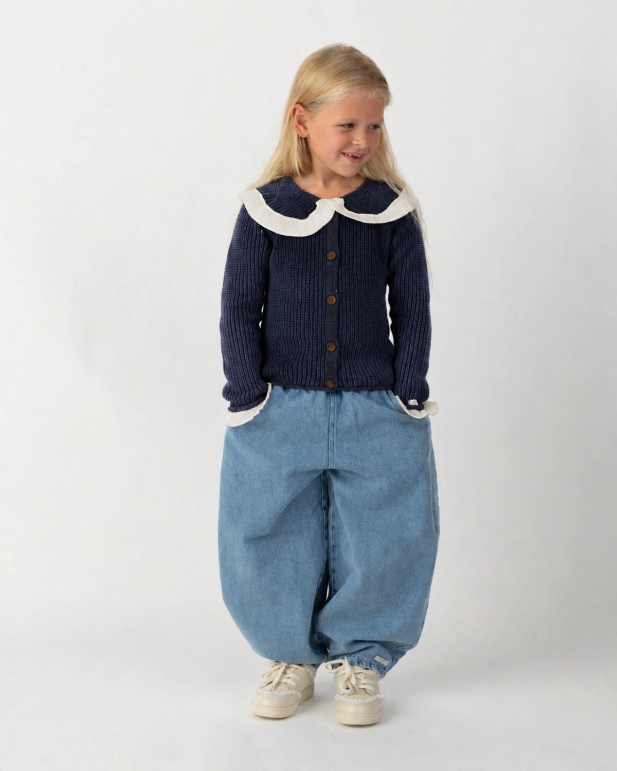 Donsje Dinotje trousers in Sky Blue, worn by a child with a navy cardigan