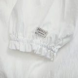 Donsje Kieke blouse in Crispy White, close-up of the ruffled cuff and brand label