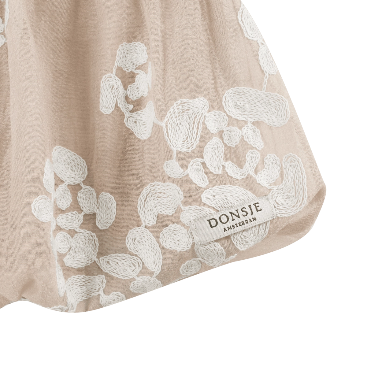 Donsje Kubwa skirt in Soft Powder with White Blossom, close-up of the floral hem and brand label