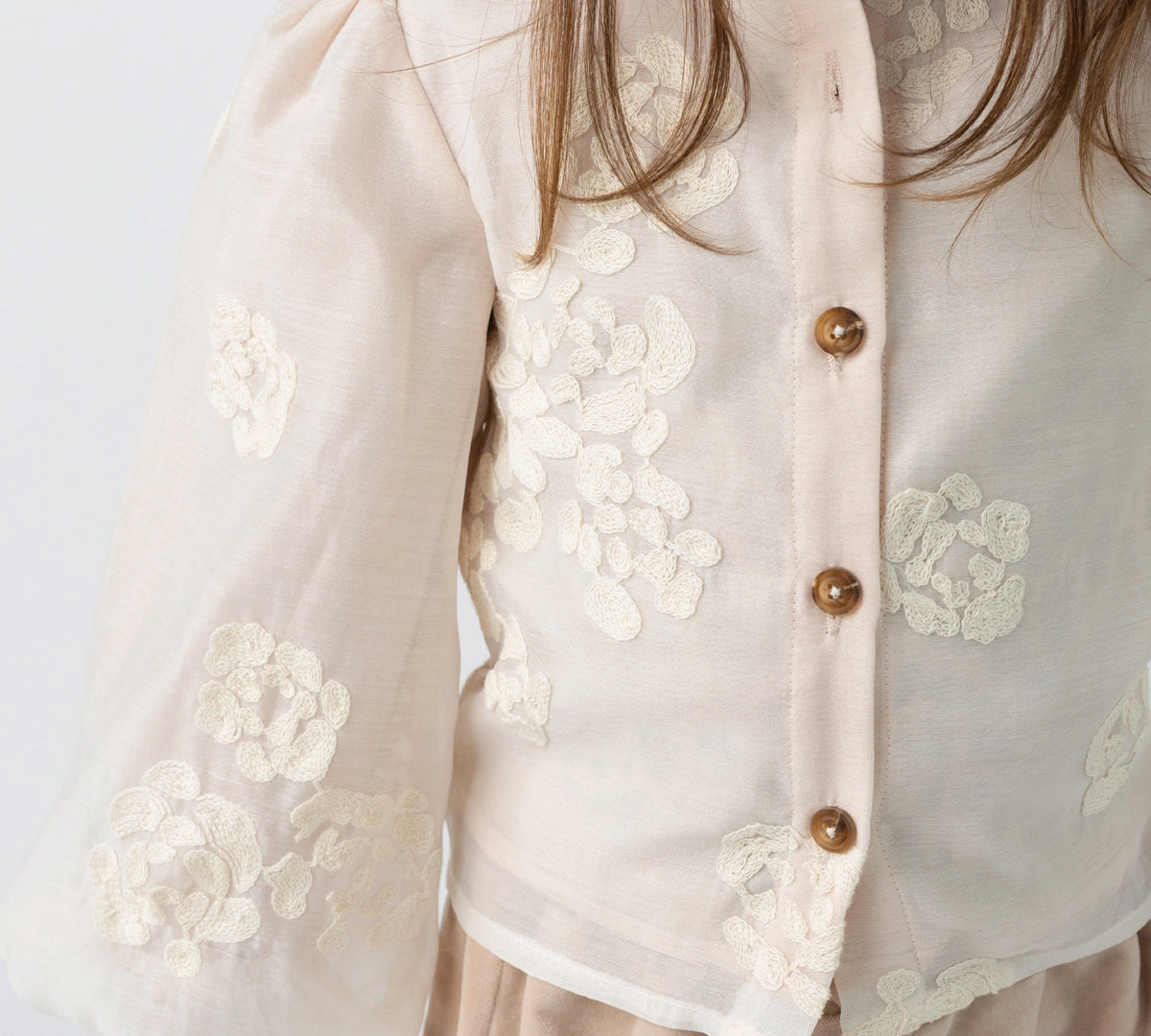 Donsje Opali blouse in Soft Powder with White Blossom, worn by a child, close-up of the blouse