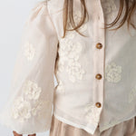 Donsje Opali blouse in Soft Powder with White Blossom, worn by a child, close-up of the blouse