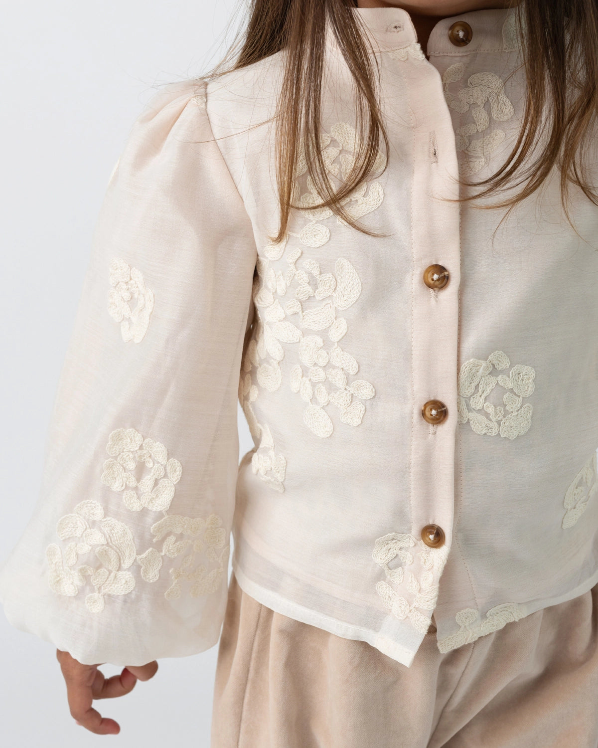 Donsje Opali blouse in Soft Powder with White Blossom, worn by a child, close-up of the blouse
