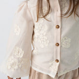 Donsje Opali blouse in Soft Powder with White Blossom, worn by a child, close-up of the blouse