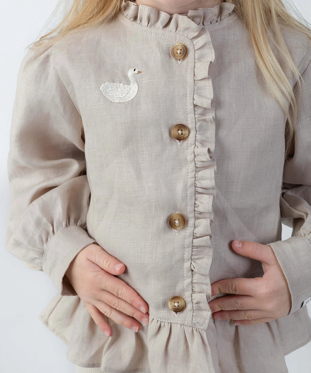 Donsje Siles Swan blouse in Soft Taupe, worn by a child, close-up of the buttons and swan detail