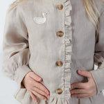 Donsje Siles Swan blouse in Soft Taupe, worn by a child, close-up of the buttons and swan detail