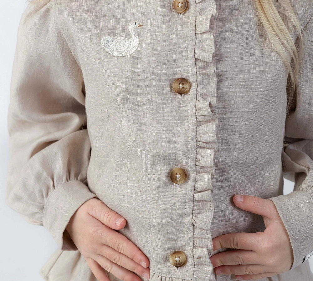 Donsje Siles Swan blouse in Soft Taupe, worn by a child, close-up of the buttons and swan detail