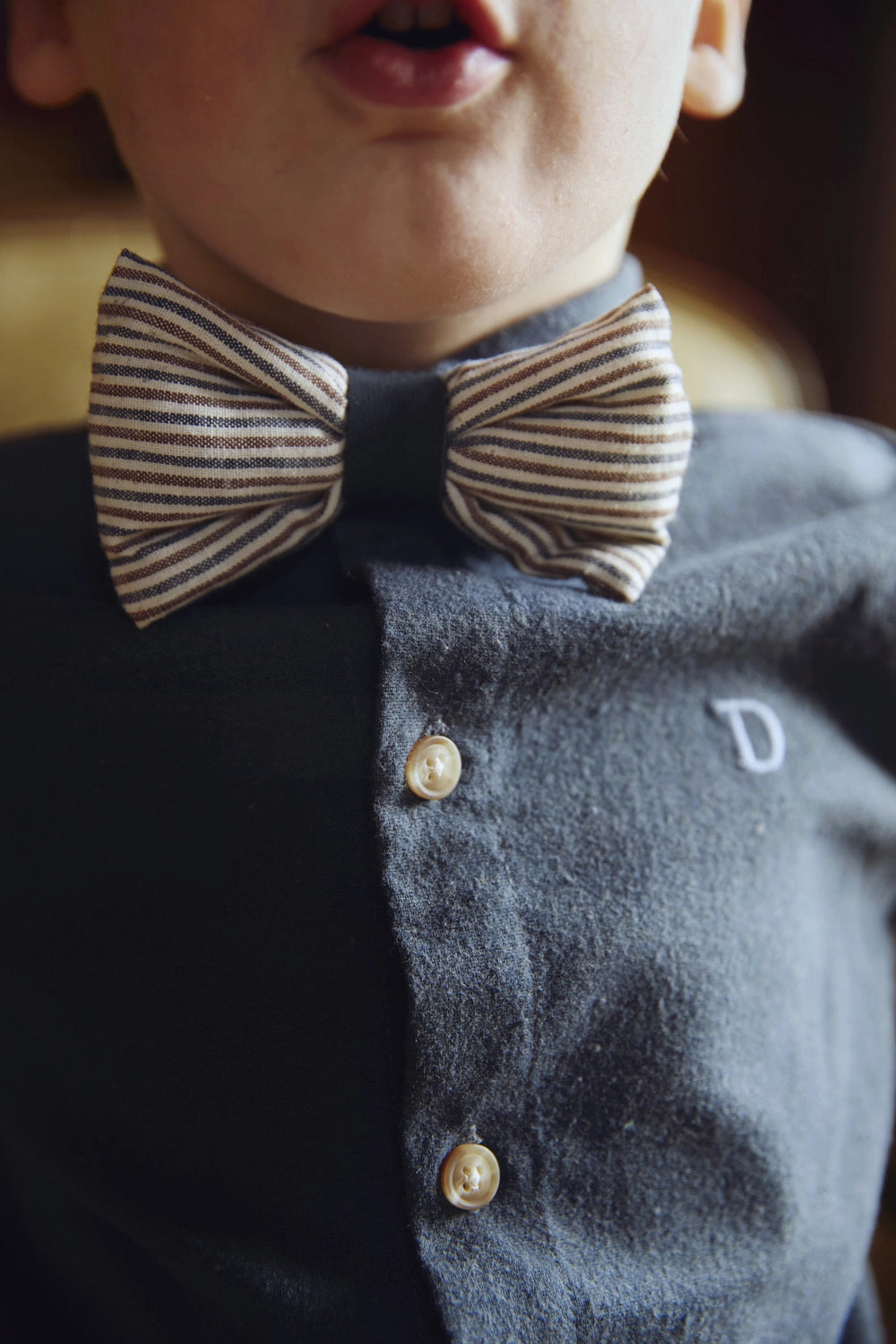 Donsje Zefrin bow tie in Navy and Burgundy Thin Striped, worn by a child with a blue shirt