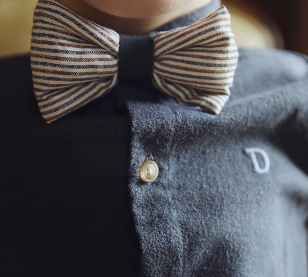 Donsje Zefrin bow tie in Navy and Burgundy Thin Striped, worn by a child with a blue shirt