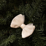 Donsje Angeline bow hairclip in Off White Metallic Leather, styled on green foliage