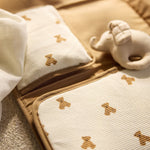 Jollein Little Waffle Mini Teddy Bear changing pad opened on a bed beside a teddy bear rattle
