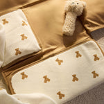 Jollein Little Waffle Mini Teddy Bear changing pad with the Natural Teddy Bear rattle on a bed