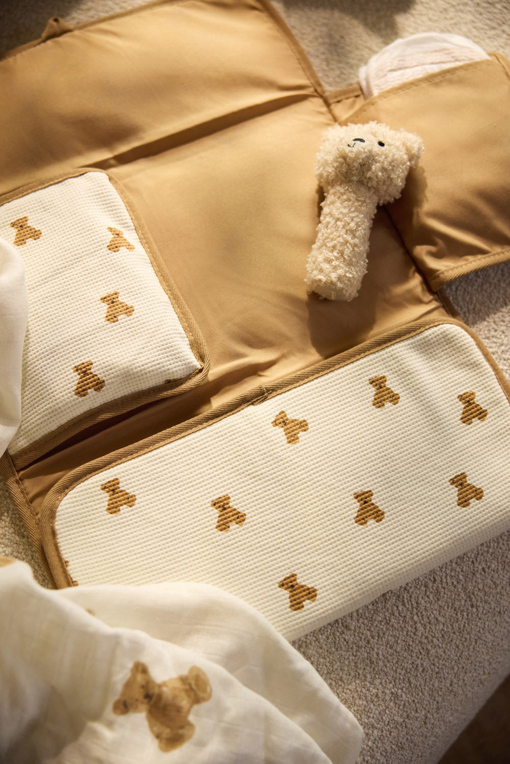 Jollein Little Waffle Mini Teddy Bear changing pad with the Natural Teddy Bear rattle on a bed