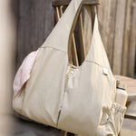 Jollein Urban diaper bag in Warm Sand displayed on a wooden bench
