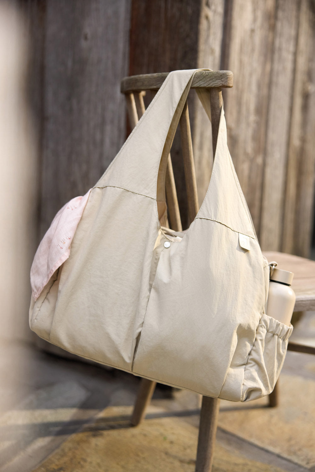 Jollein Urban diaper bag in Warm Sand displayed on a wooden bench