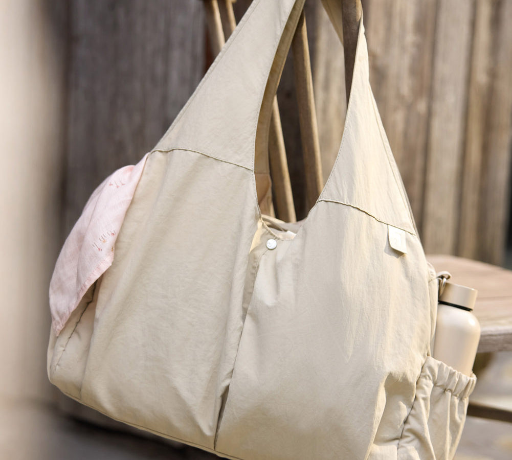 Jollein Urban diaper bag in Warm Sand displayed on a wooden bench