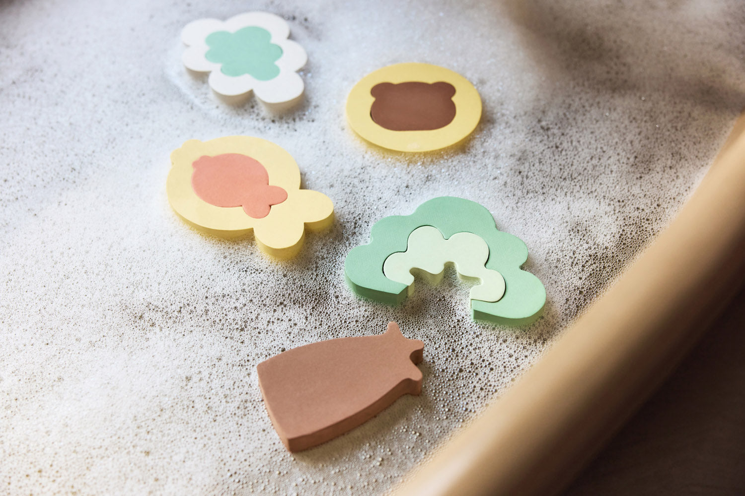 Close-up of colourful Jollein Kangaroots foam bath puzzle pieces on a bath edge