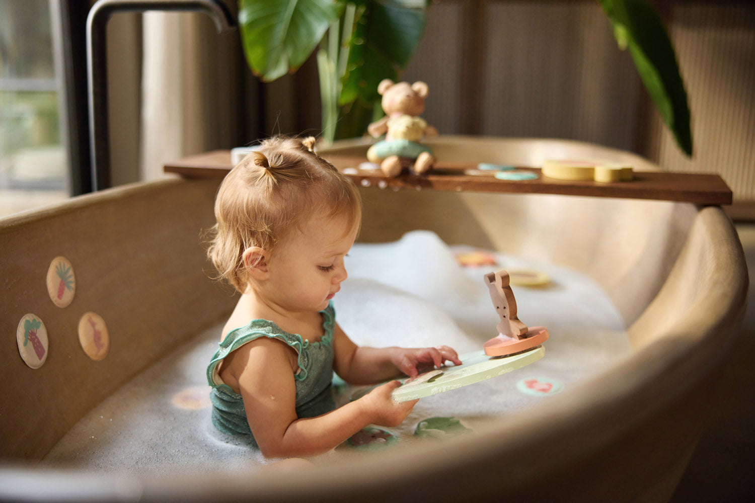 Child holding a figure from the Jollein Kangaroots bath foam playset in a bathtub