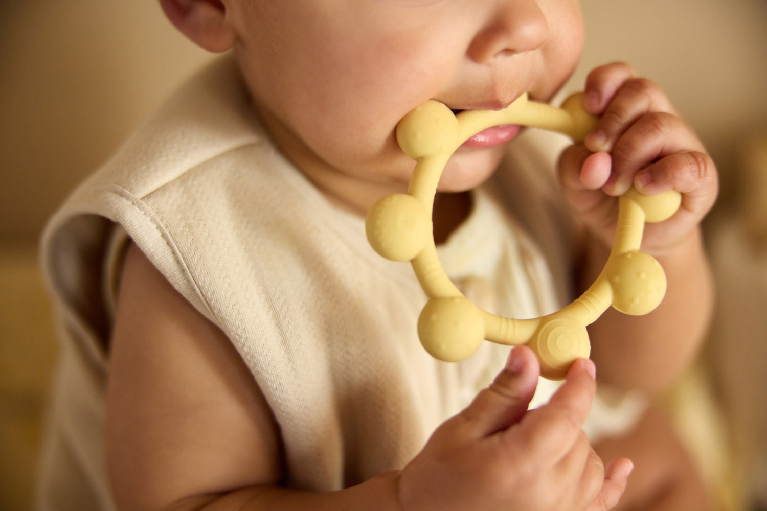 Baby holding the Jollein Vanilla sun silicone teething ring