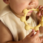 Baby holding the Jollein Vanilla sun silicone teething ring