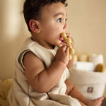 Baby seated while holding the Jollein Vanilla sun silicone teething ring near their mouth
