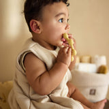 Baby seated while holding the Jollein Vanilla sun silicone teething ring near their mouth
