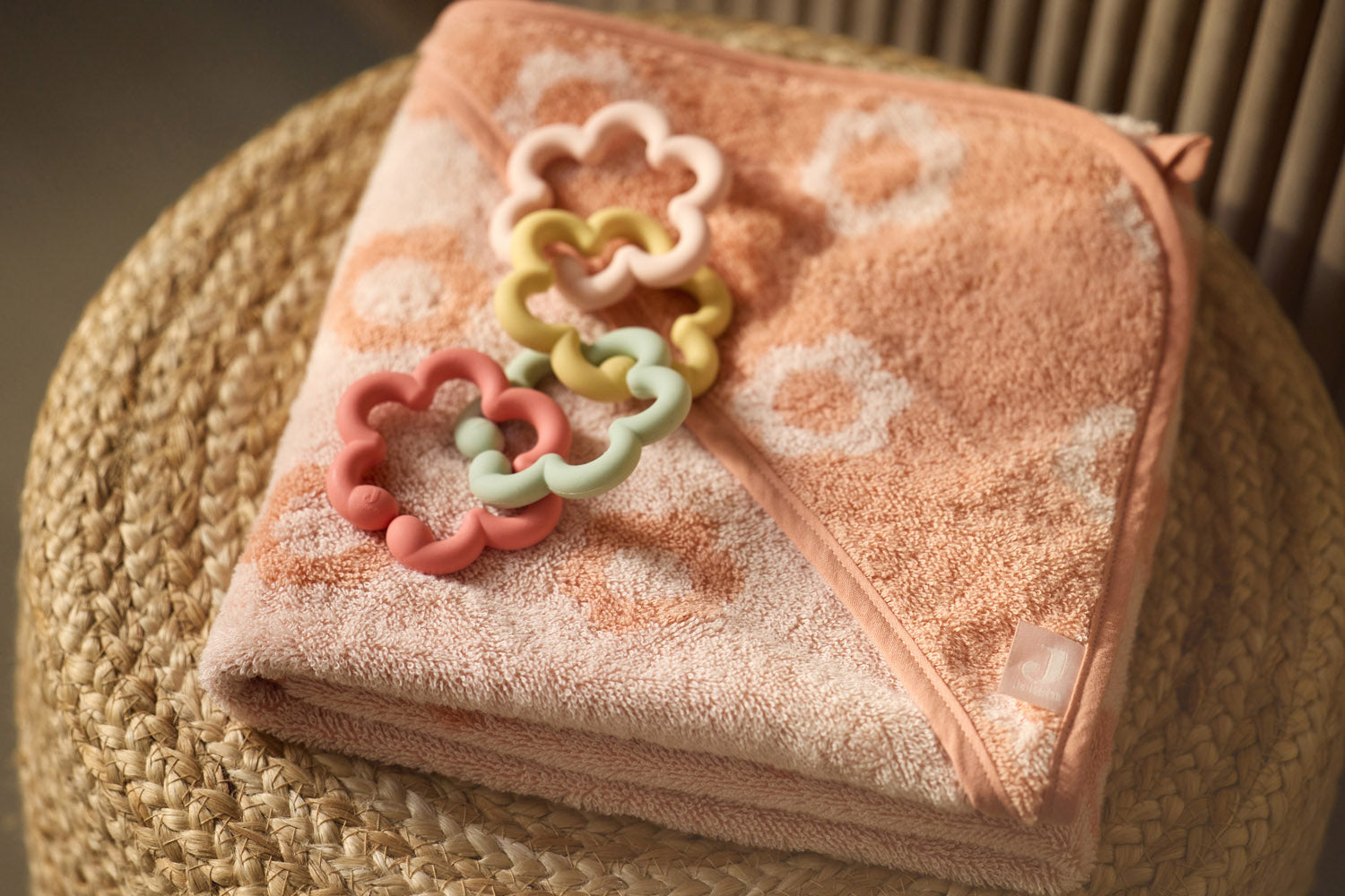 Jollein silicone flower toy loops on a pink patterned blanket in a wicker basket