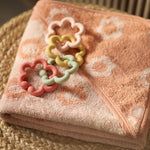 Jollein silicone flower toy loops on a pink patterned blanket in a wicker basket