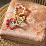 Jollein silicone flower toy loops on a pink patterned blanket in a wicker basket