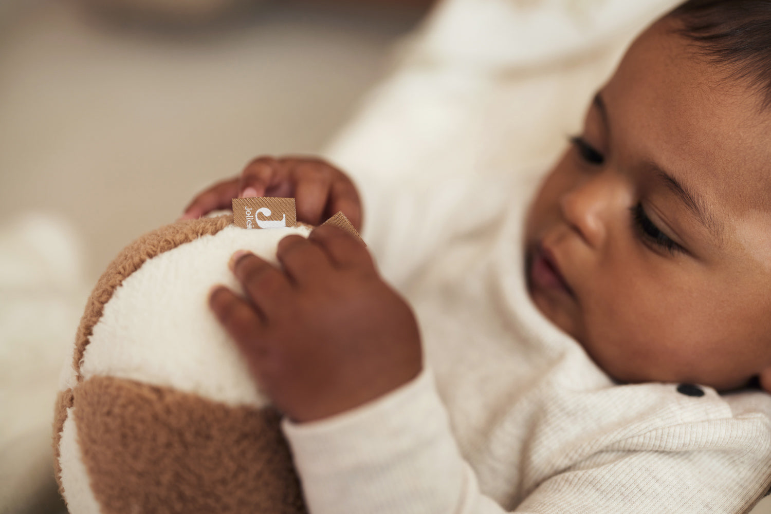 close up of a baby holding the Jollein soft play ball in ivory and biscuit 